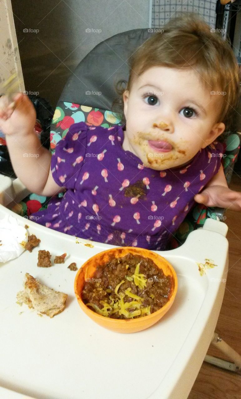 Messy dinner. toddler eats chili and bread.