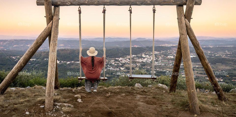 A woman on a swing enjoys golden hour and the view across the landscape.