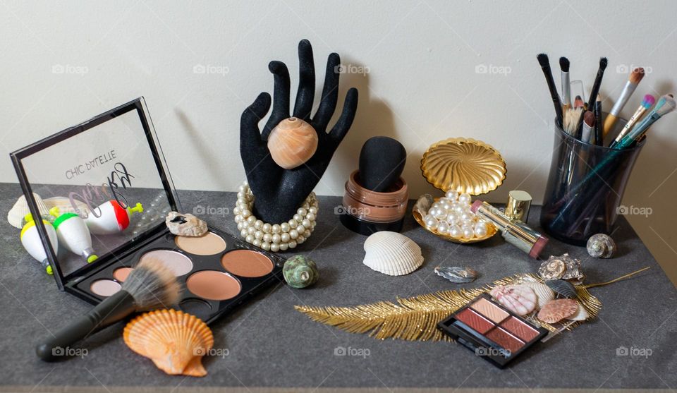 Neutral colored makeup with shells and pearls on a slate backdrop 