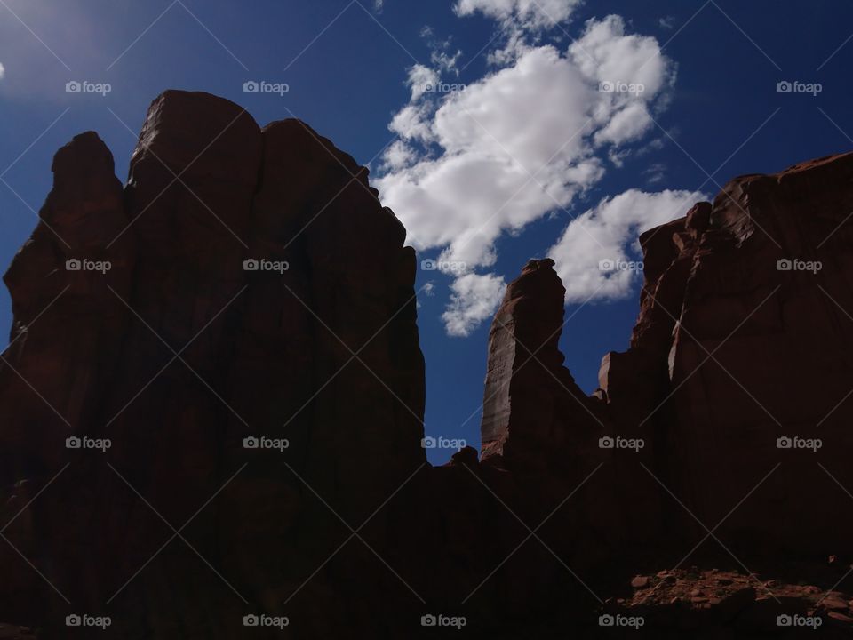 Rock formations of Monument Valley shaped by contrasting lights and shadows, intense blue sky standing as a background for those magnificent works of nature.