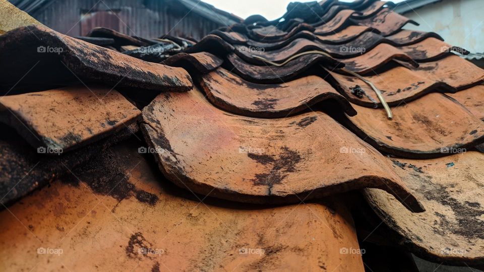 View of old school roof tiles made of clay on the roof of a house with a rickety bamboo frame, clay tiles that are generally installed on houses in Indonesia.