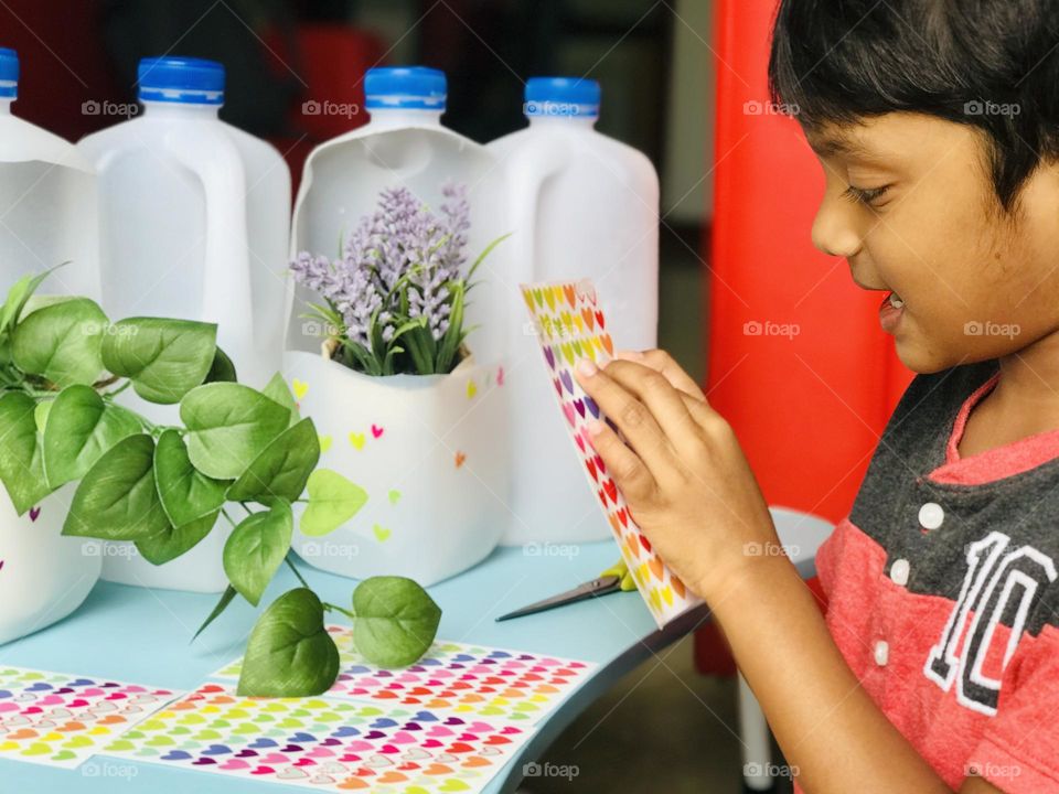 A boy doing craft with leftover milk bottles.