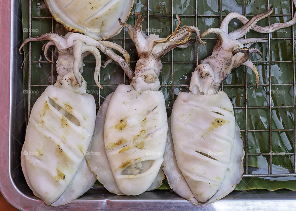 Fresh squid grilled on the steel mesh.