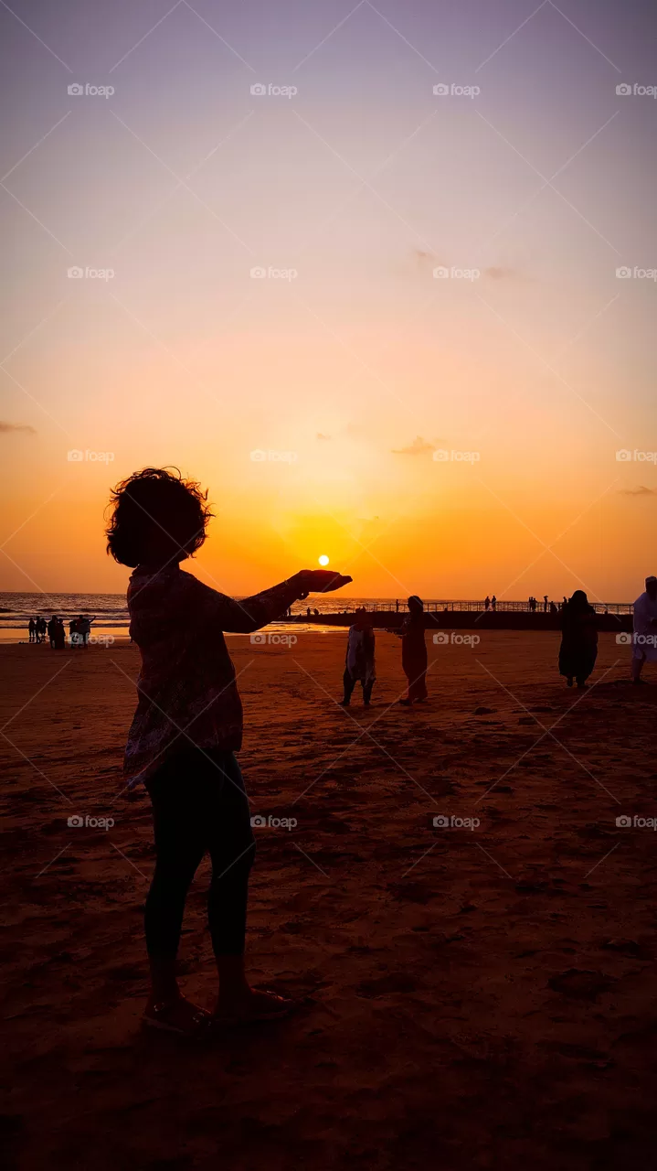 Catching Sun in Hands in evening at Beach