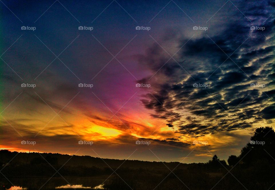 Colorful sunrise with inky sky. Colorful lakeside sunrise with black inky clouds