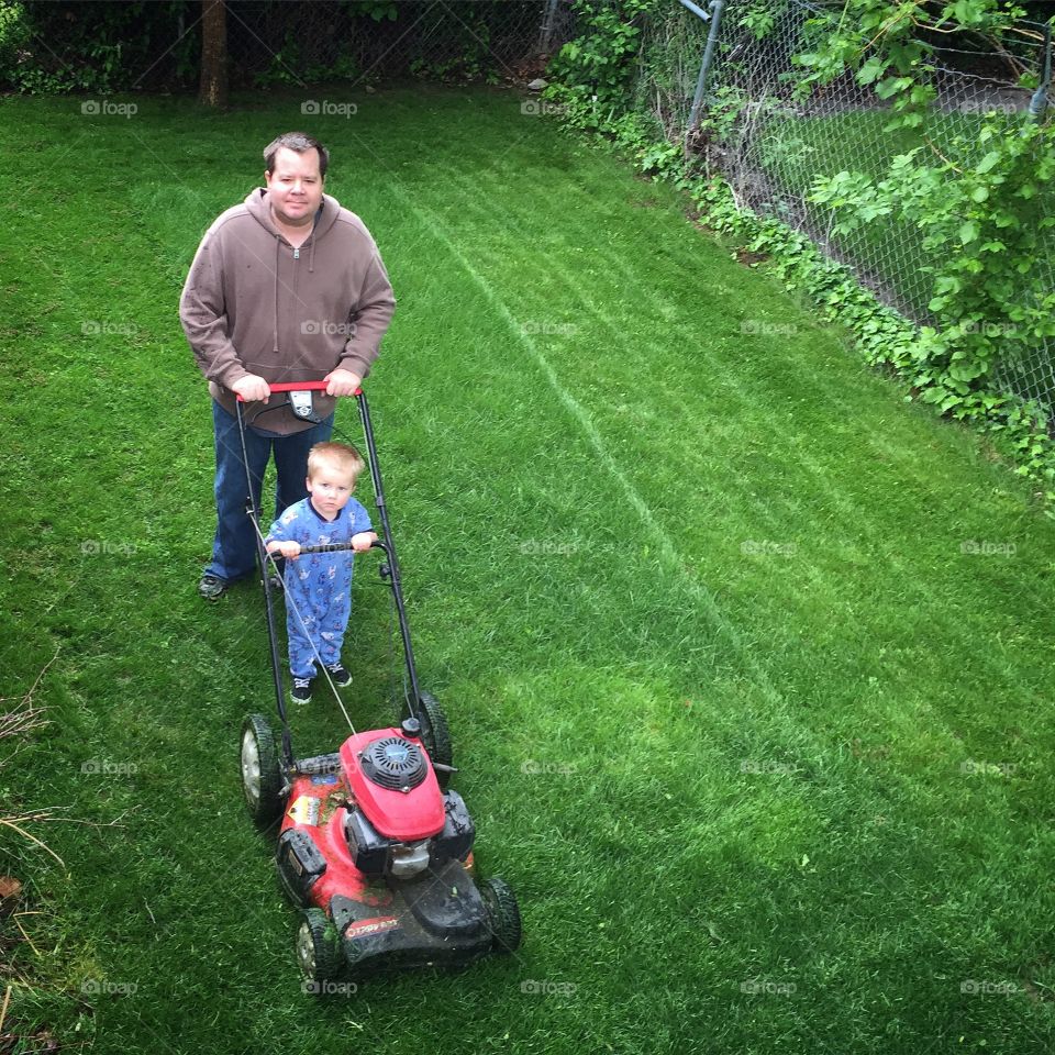 Like Father Like Son. Father and son mowing the lawn together