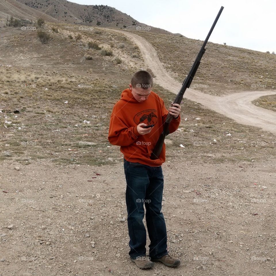 redneck yuppie . my son taking a moment to check his cell phone between target practice