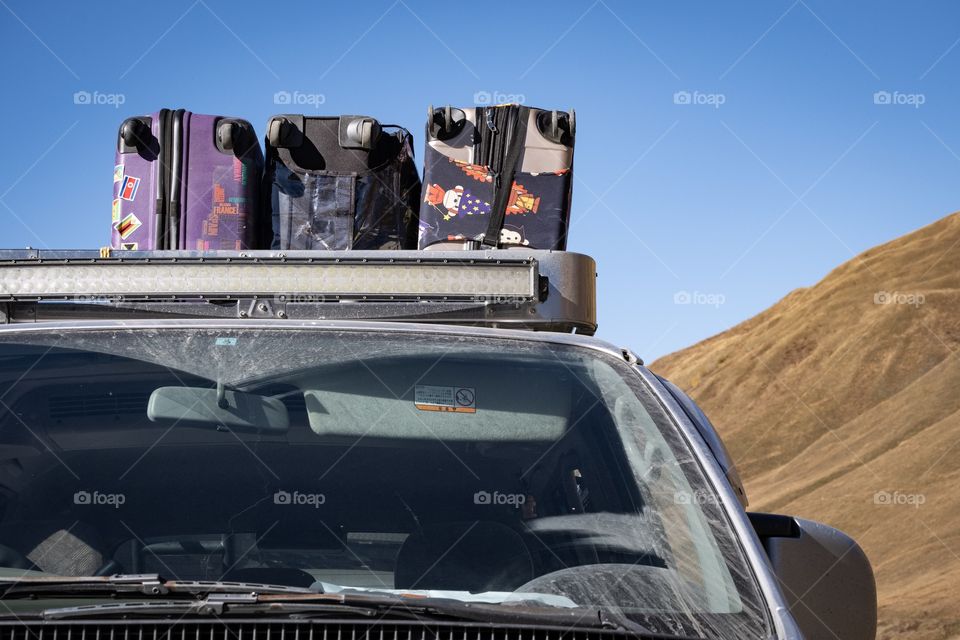 Traveler’s suitcases on 4WD roof rack in front of mountain scape