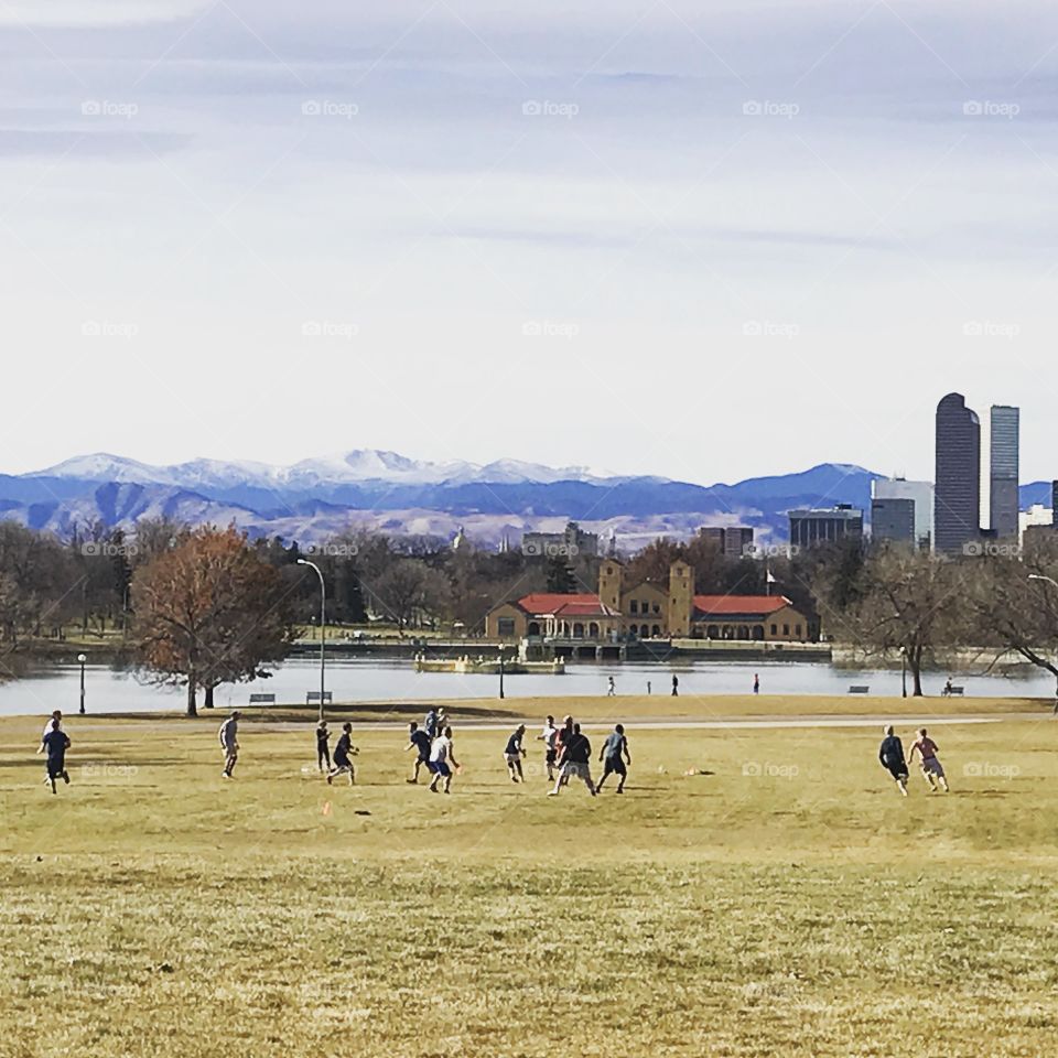 View of mountain range from Denver, CO park as boys play football on Thanksgiving 2017.