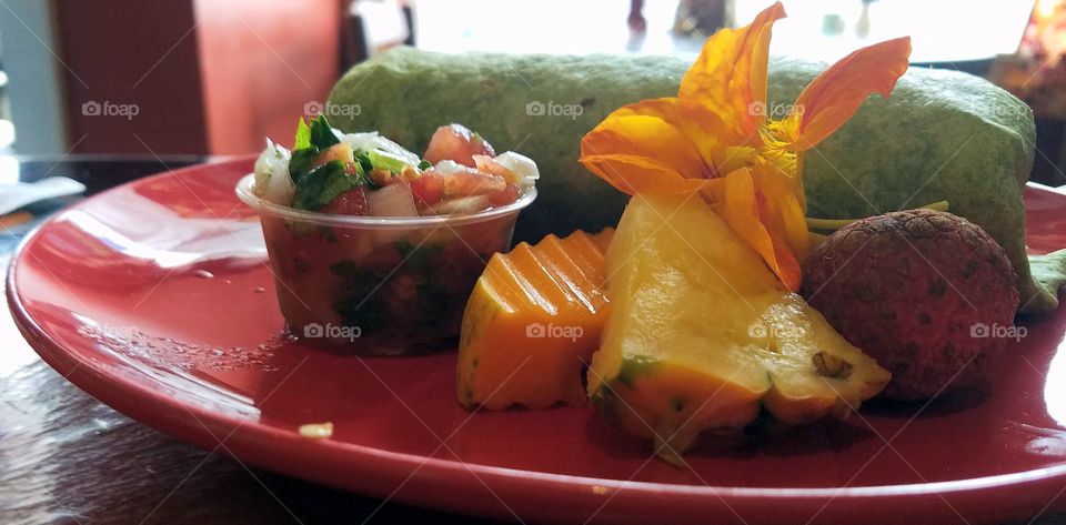 Green breakfast burrito with salsa and fruit