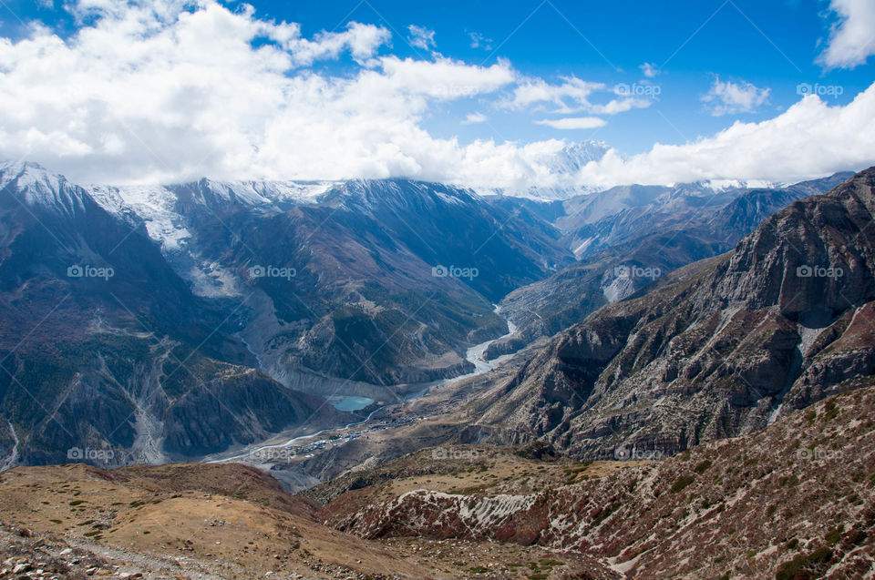 Glacier water flowing through the valley in Manang area, Nepal, in between impressive hills in the Himalaya mountain range
