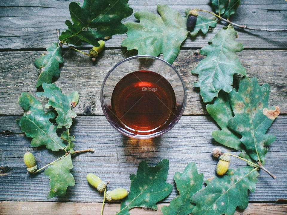 glass of whiskey and oak acorns on a wooden base