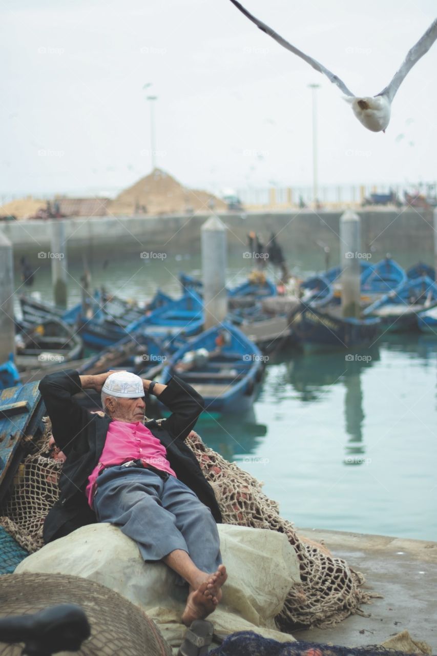 A picture of a fishing boat keeper, resting a little while the fishermen start strenuous fishing tours .. Photo taken in a Moroccan city last week .. One morning early