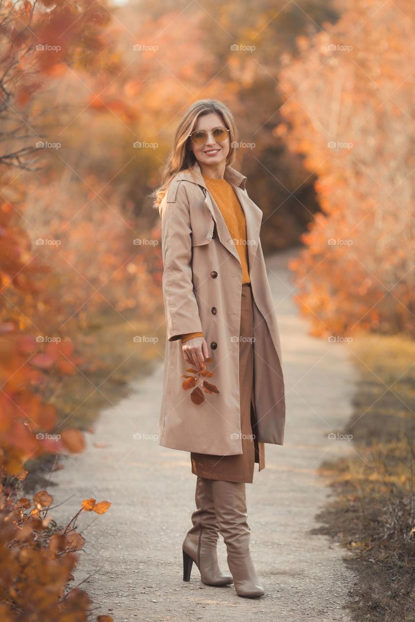 Beautiful millennial woman 35 years old in fashion clothes walking in autumn park 