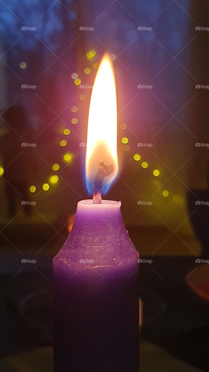 Burning purple candle with purple glare