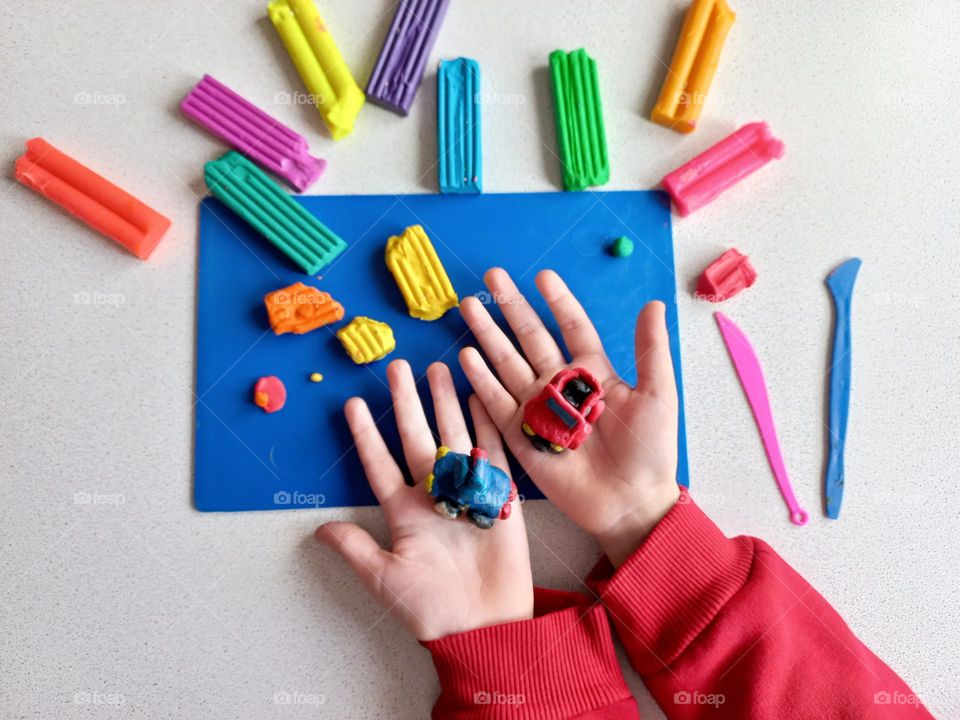 plasticine cars in the hands of a child.