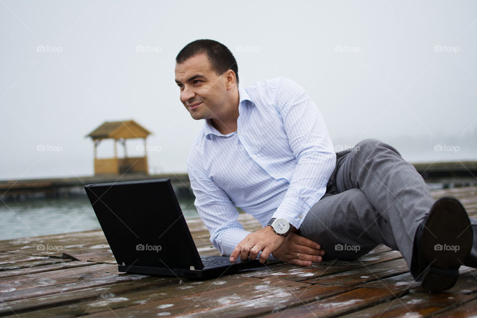 Man on lake dock with laptop