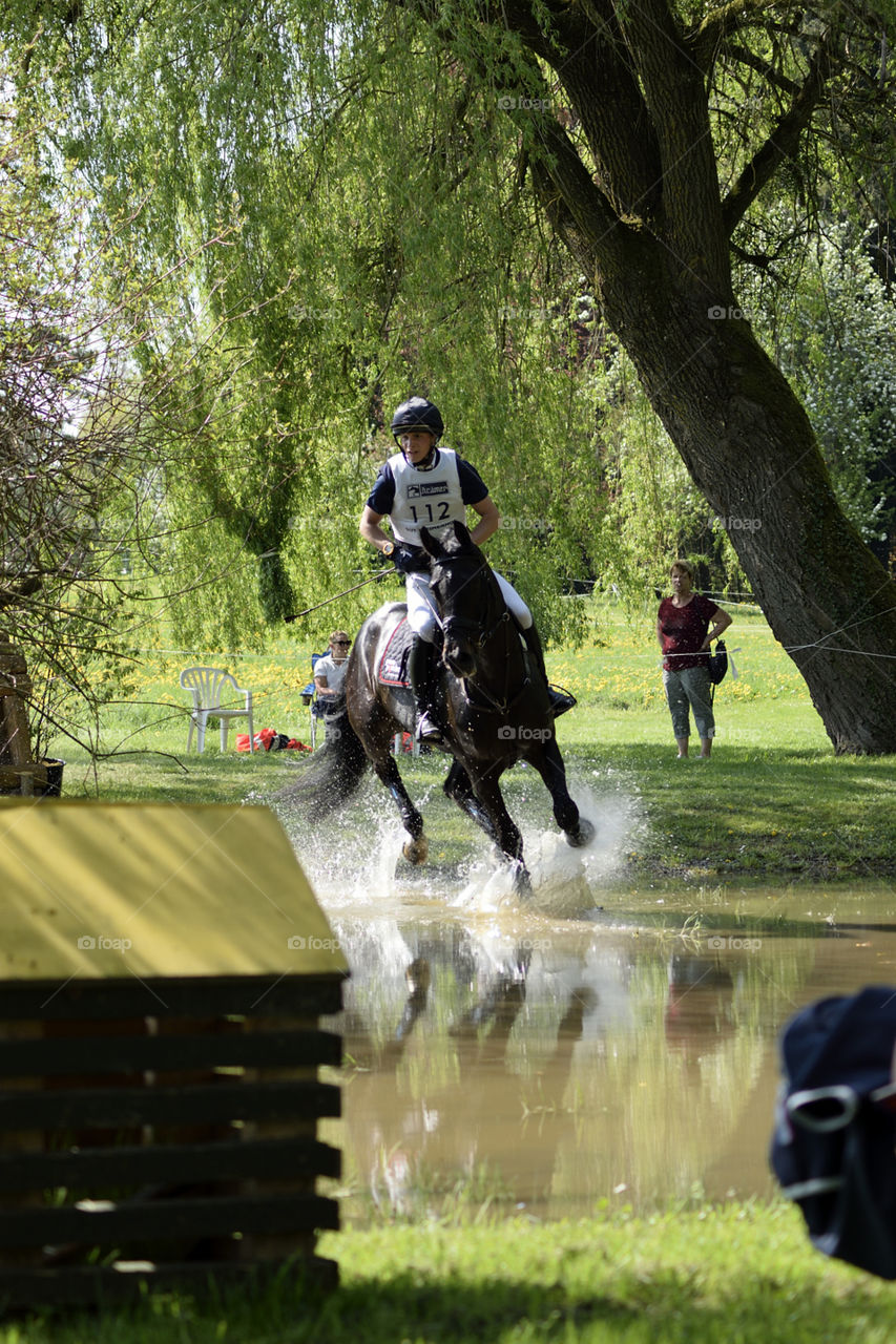 Horse gallopping through water during a military competition