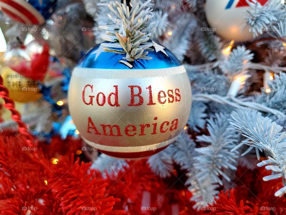 God Bless America ornament hanging on a patriotic red, white and blue Christmas tree