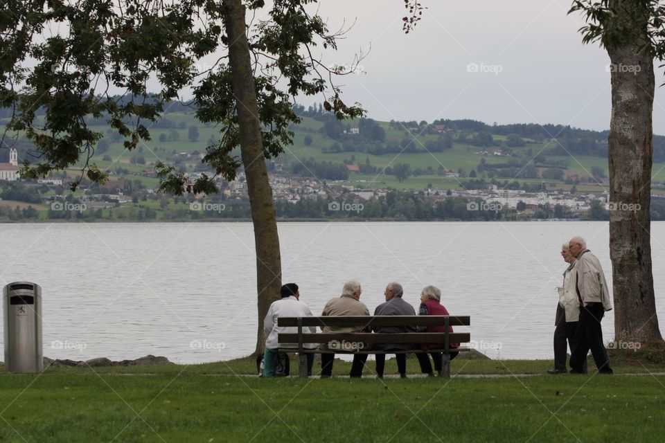 Elderly People. Elderly people sitting on a bench facing the lake Sempachersee in Luzern,central Switzerland.