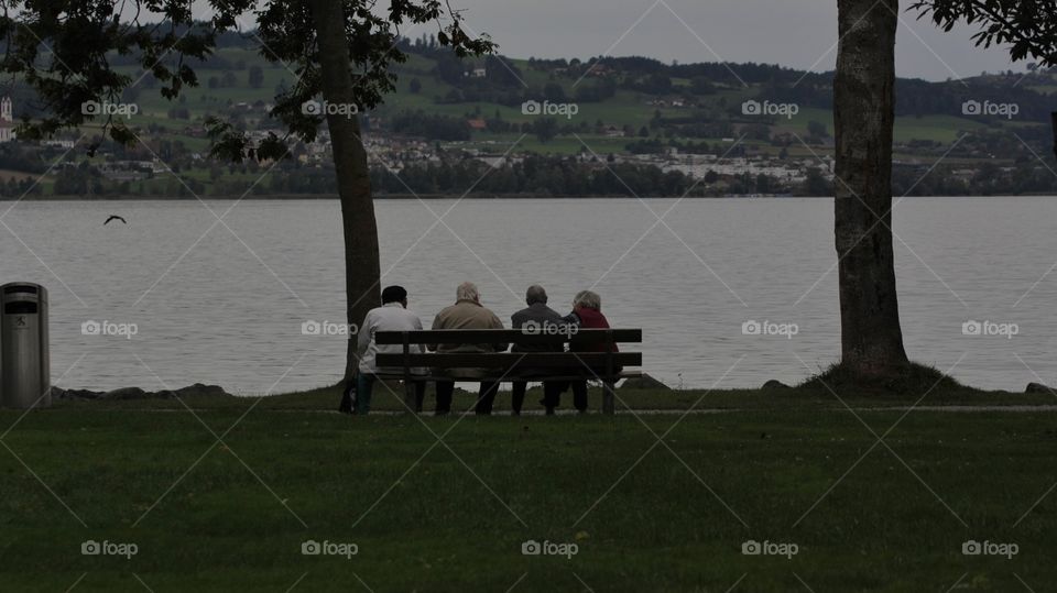 Elderly People. Elderly people sitting on a bench facing the lake Sempachersee in Luzern,central Switzerland.