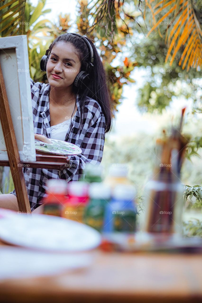 Girl enjoying painting in the middle of nature listen to music