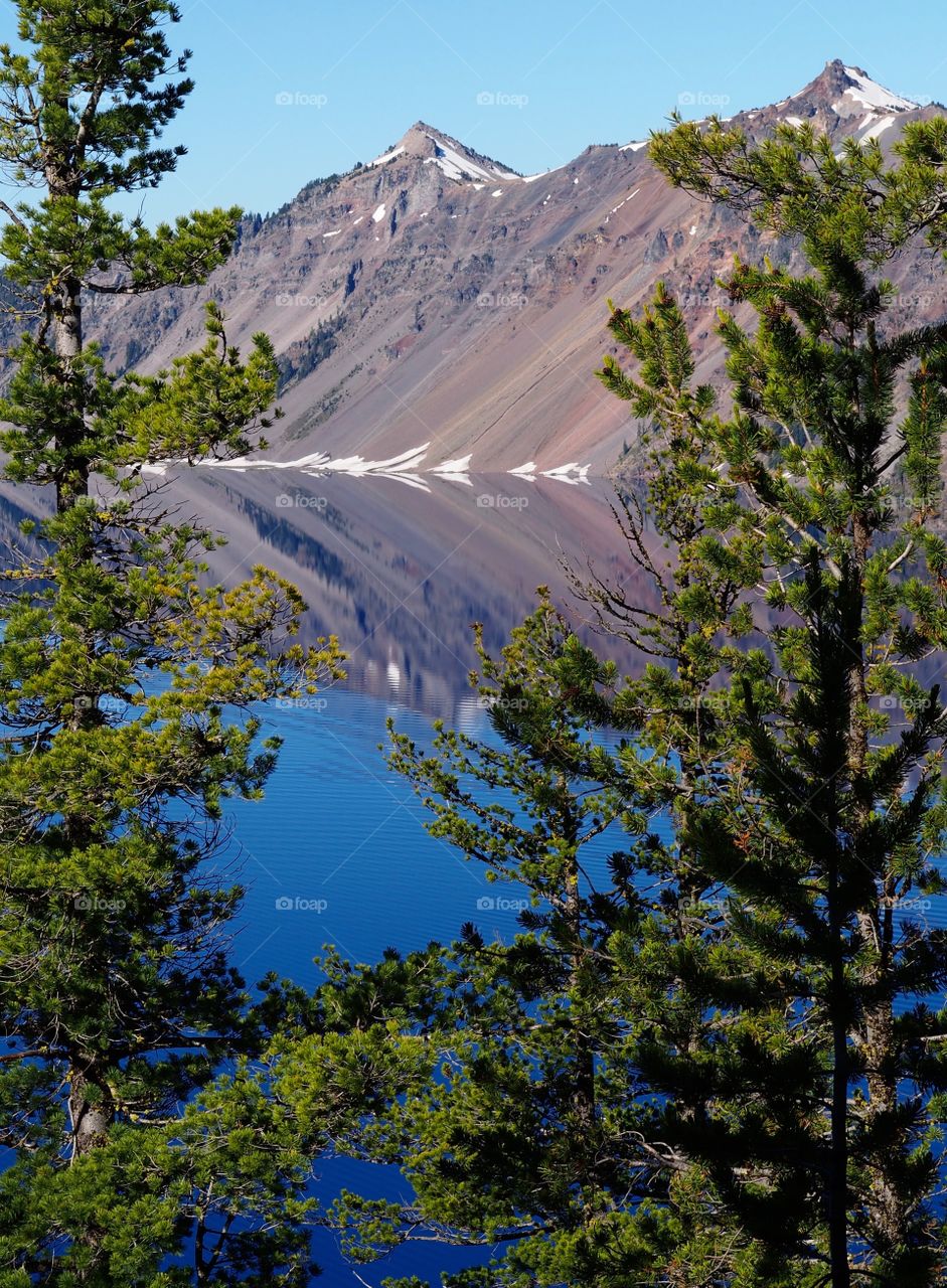 The rugged rim reflecting in the stunning Crater Lake on a beautiful summer morning in Southern Oregon. 