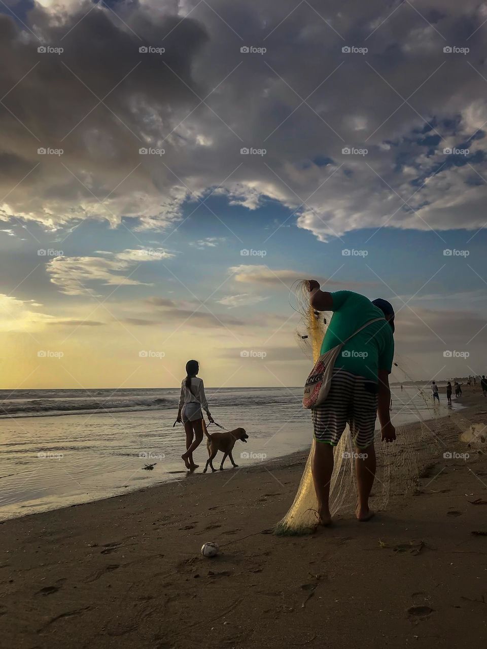 a dog and its owner walking along the beach during sunset time in Kuta, Bali, Indonesia