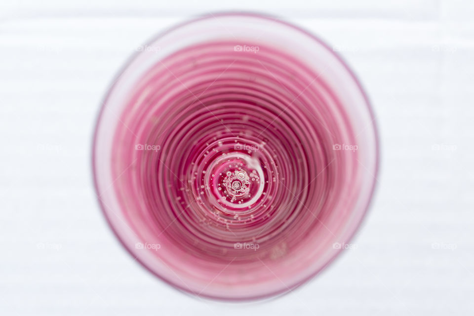 Round, pink striped glass filled with sparkling water