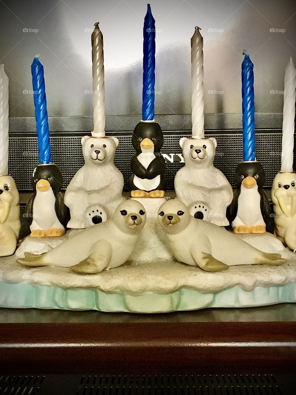 Chanukah menorah keepsake is a handcrafted and painted ceramic display in the form of a snowcovered polar iceberg for the base populated with polar animals (penguins, polar bears, seals and walrus) which serve as candle holders.