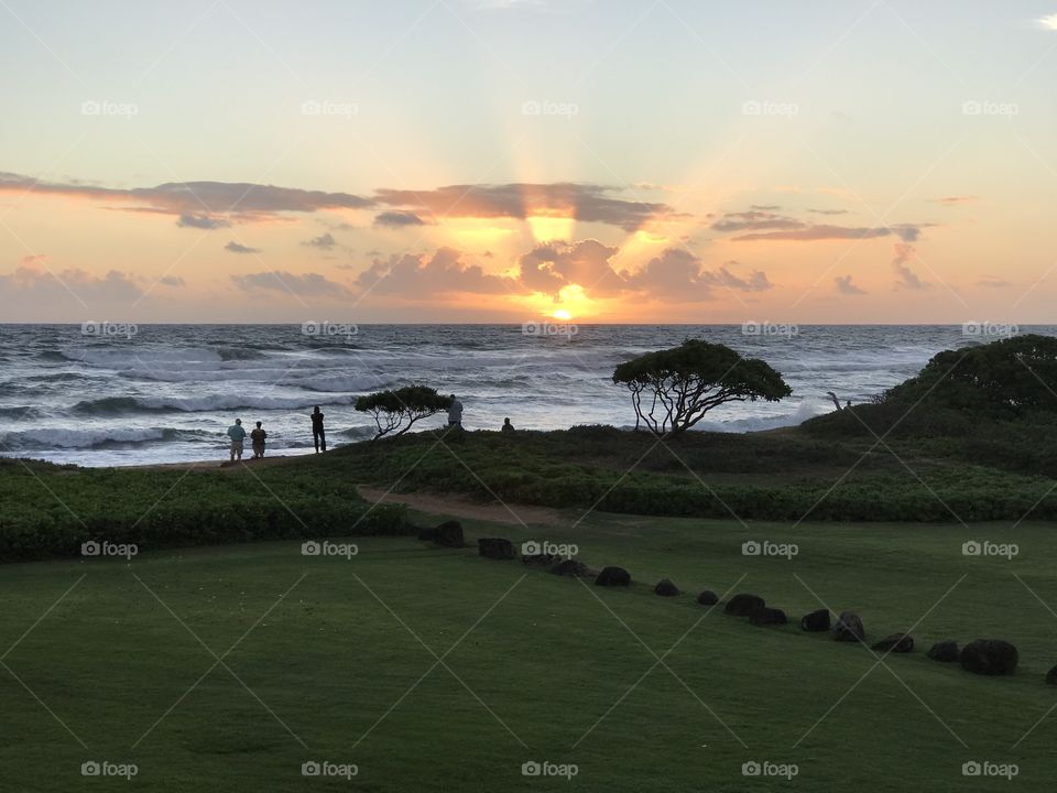 Sunrise streaks the sky with vivid color at a beach in Kauai. 