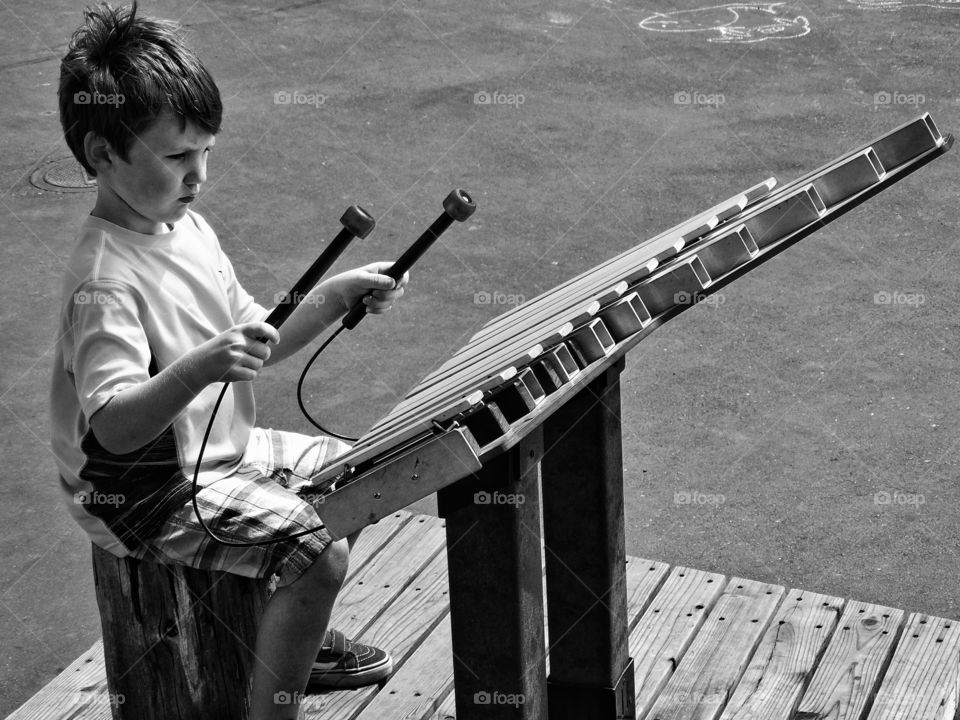 Young Street Musician. Young Boy Playing A Large Metal Xylophone
