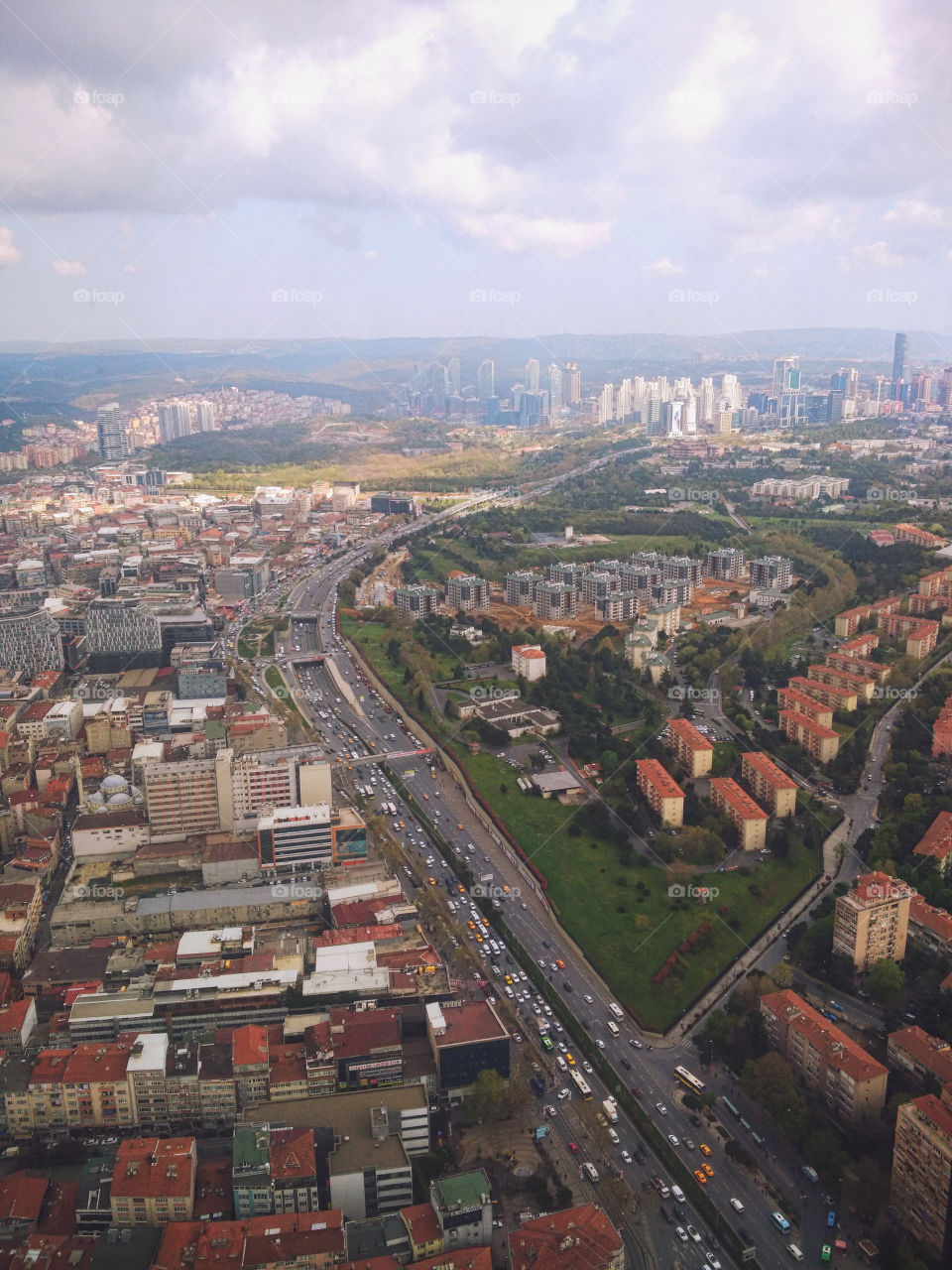 A view from the window of a high-rise building on a multi-million dollar city with roads, avenues, skyscrapers and houses with red roofs.  Urban studies.