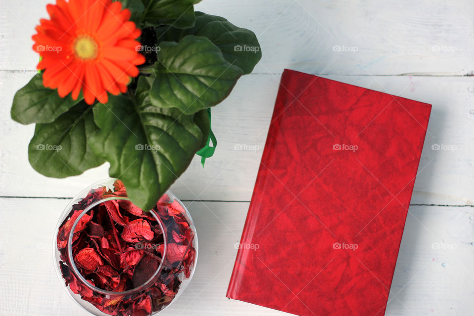 Beautiful flower and red book on a white table