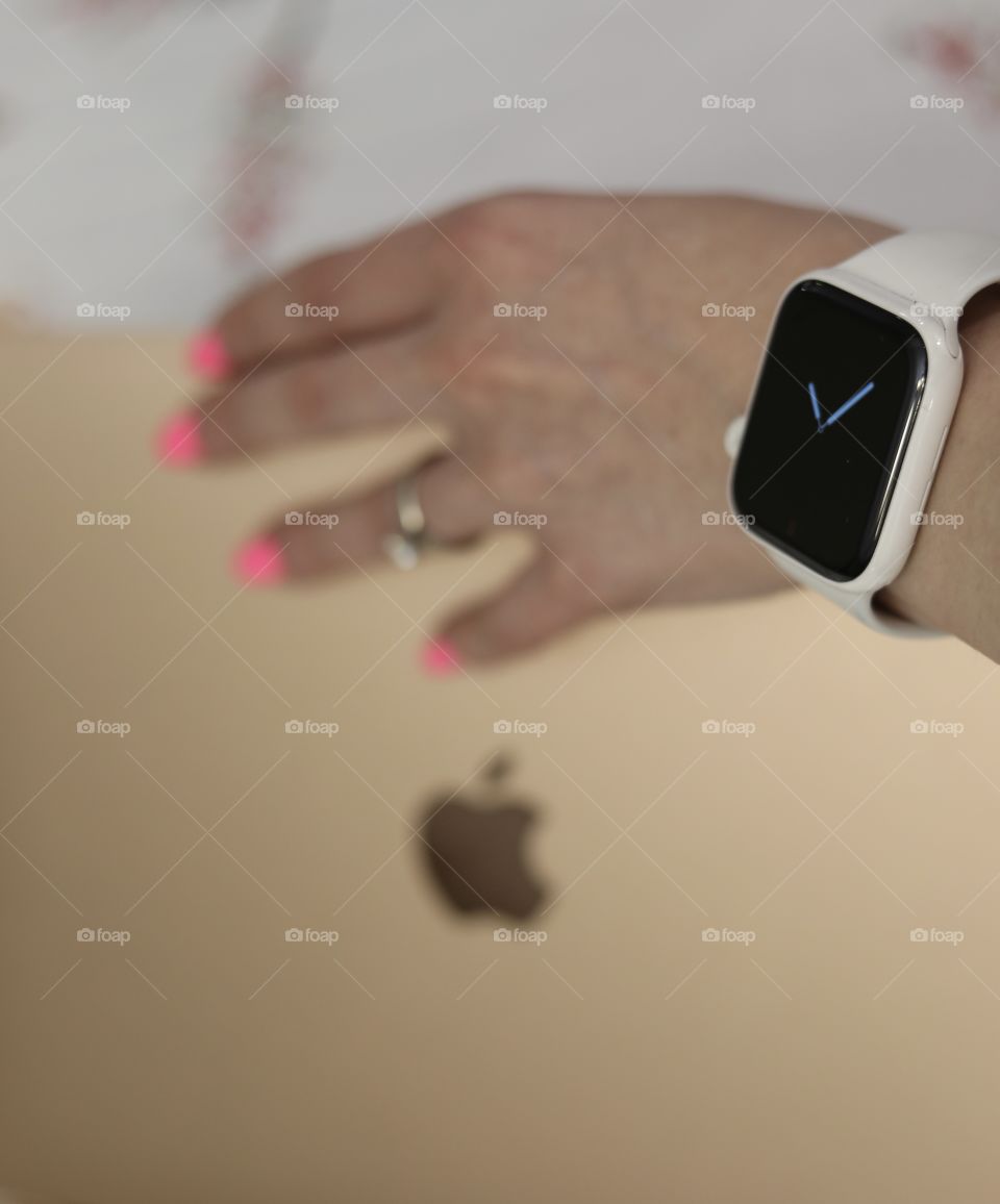 Woman wearing Apple Watch Gen 5 grabbing rose gold MacBook Air