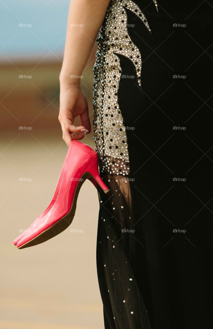 Pink Shoes. Young woman wearing a black dress holding pink shoes