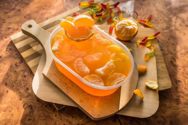 Delicious orange jelly with tangerine slices in a container and jelly worms.