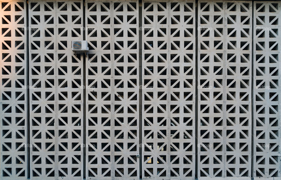 Abstract photo of an administrative building with triangular windows, on which there is one single air conditioner