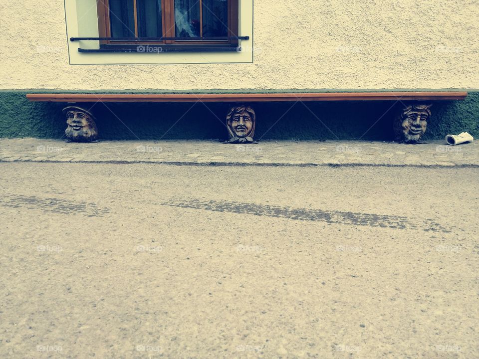 Unusual bench with original legs in the shape of seniors heads. Free space for a text.