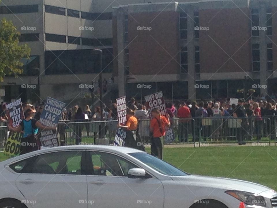 Westboro Baptist church members holding signs to protest an LGB club formed by students of IUPUI. Club supporters and spectators stand in the background.