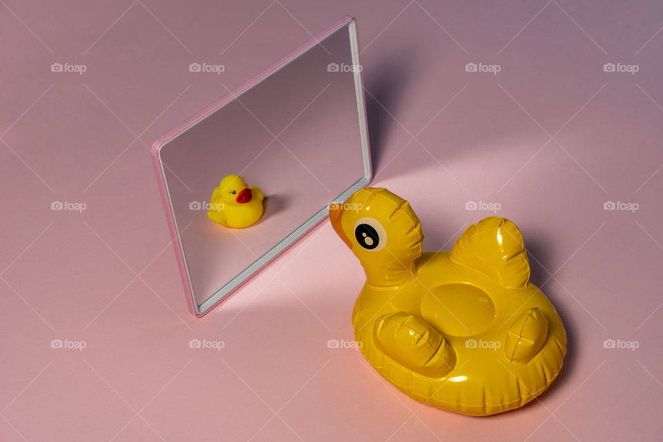 Rubber yellow duck with tiny projection of self in mirror