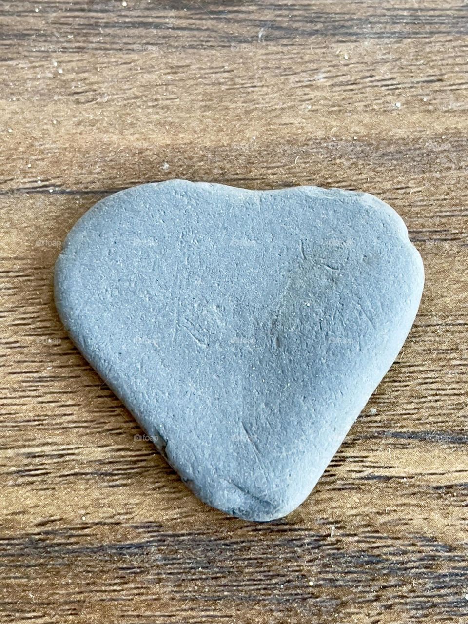 Abstract Heart shaped grey rock stone on old oak wood surface, blank suitable for background and added copy text 