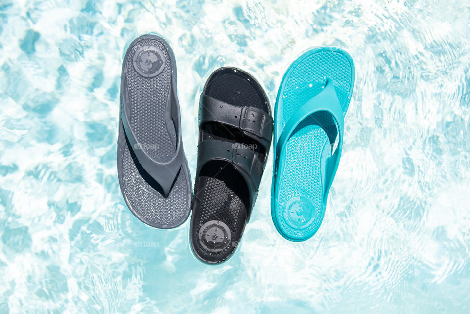 Flat lay of women's sandals floating on top of an outdoor swimming pool