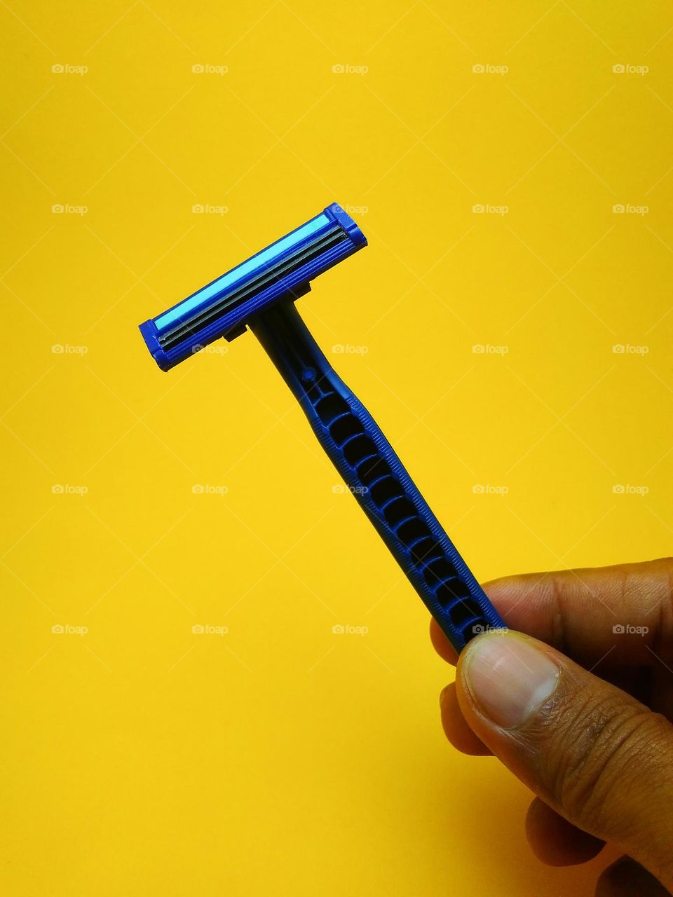 a mustache trimmer with two sharp blades in a man's hand. Photographed in the studio on a yellow background.