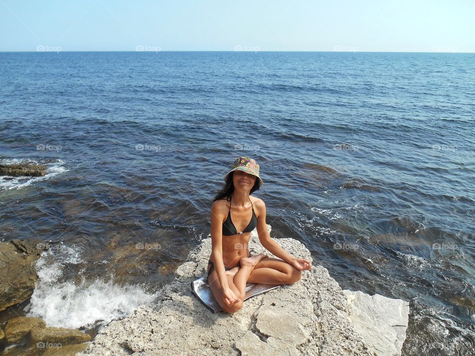 girl in yoga lotus on a sea stone rock summer time