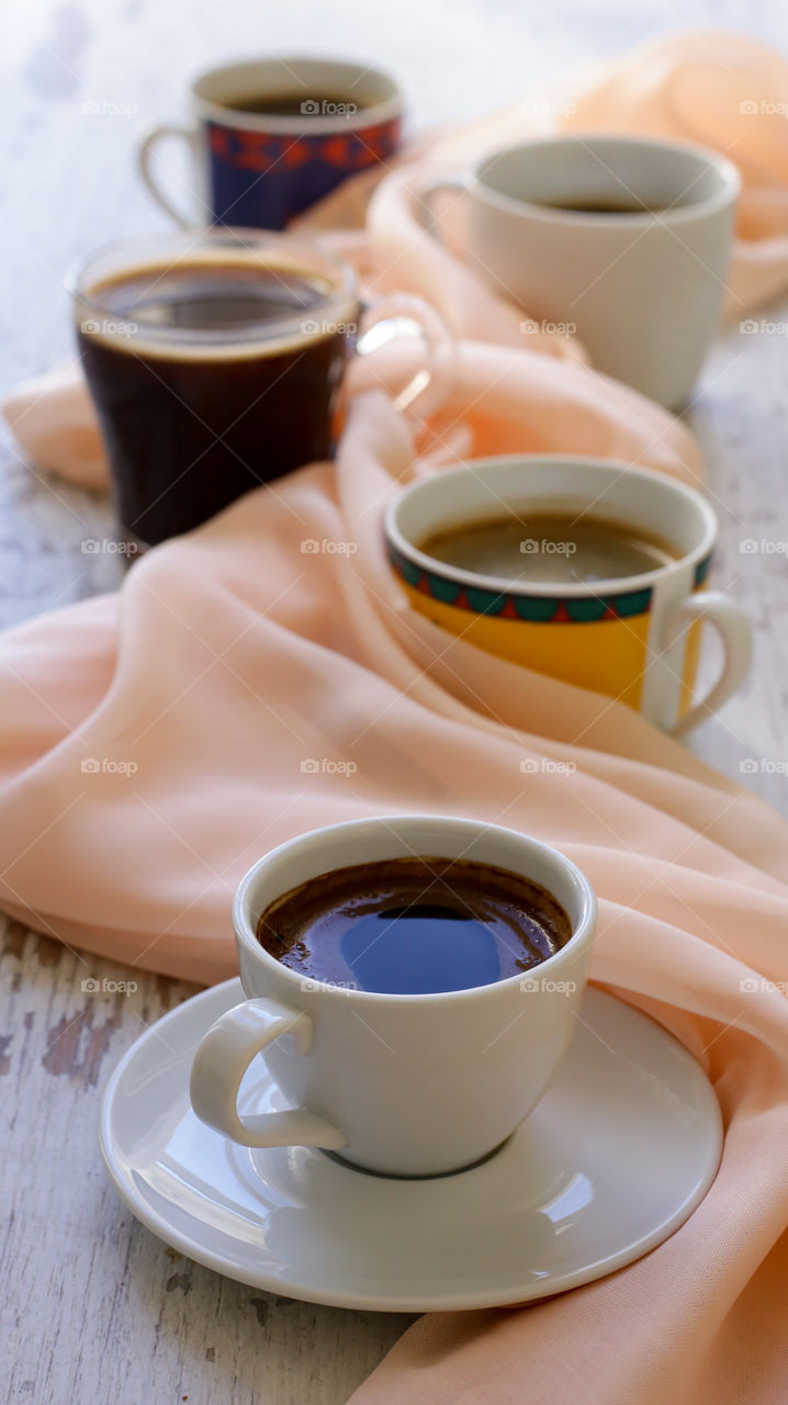 four mugs of coffee and beige cloth