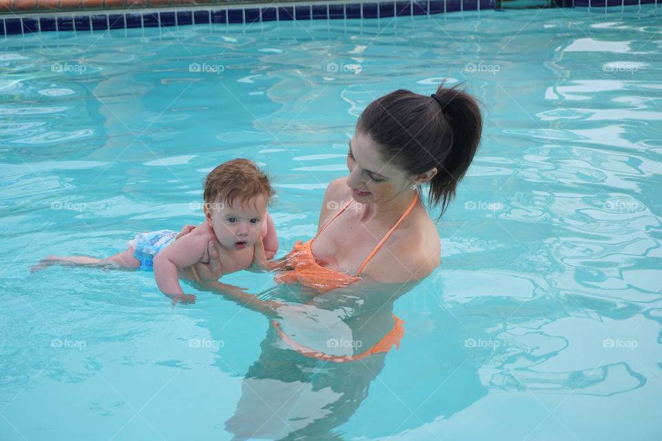 Mother holding her baby in swimming pool