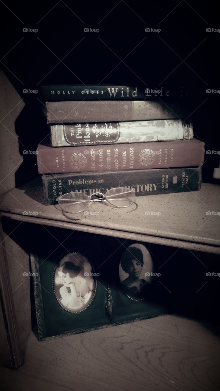Stack of books with eyeglasses and frame