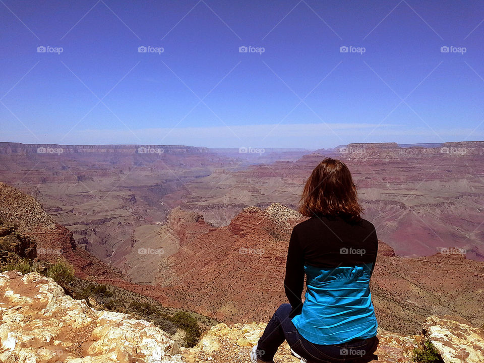 Woman sitting edge of Grand Canyon.