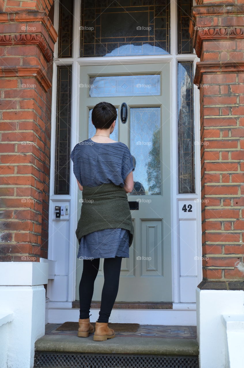 Female canvasser knocking on a green door and standing outside